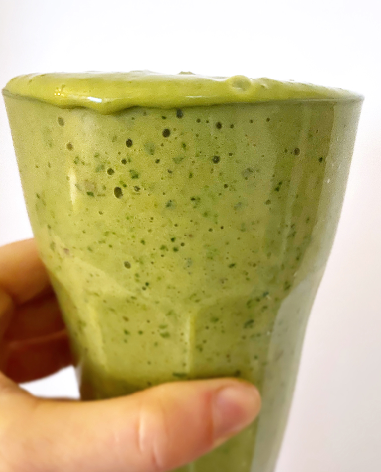 Ett glas med grön vegansk smoothie.