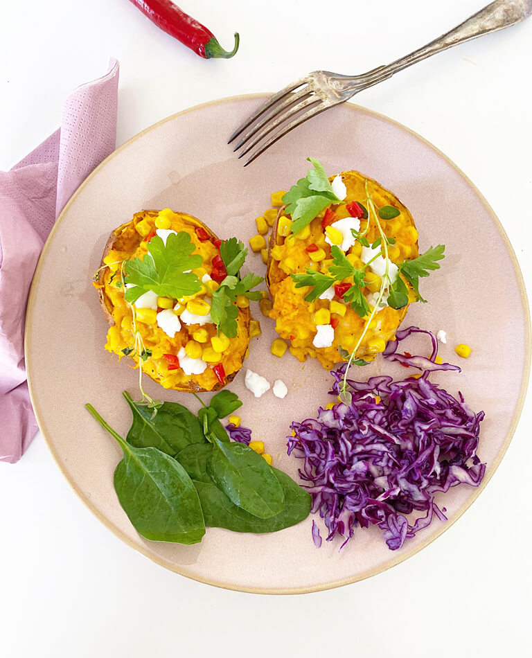 Ett fat med ugnsbakad sötpotatis med majs och vegansk fetaost.