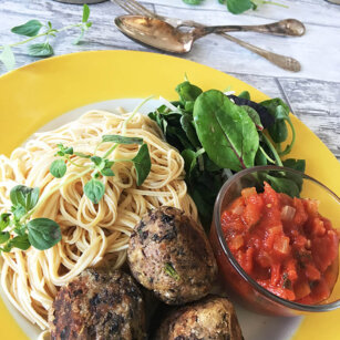 Ett gult fat med vegobullar /bönbullar med spagetti och tomatsås.