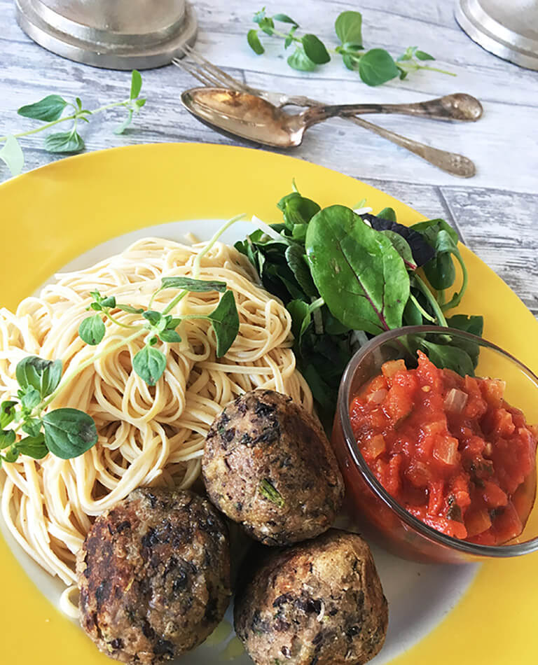 Ett gult fat med vegobullar /bönbullar med spagetti och tomatsås.