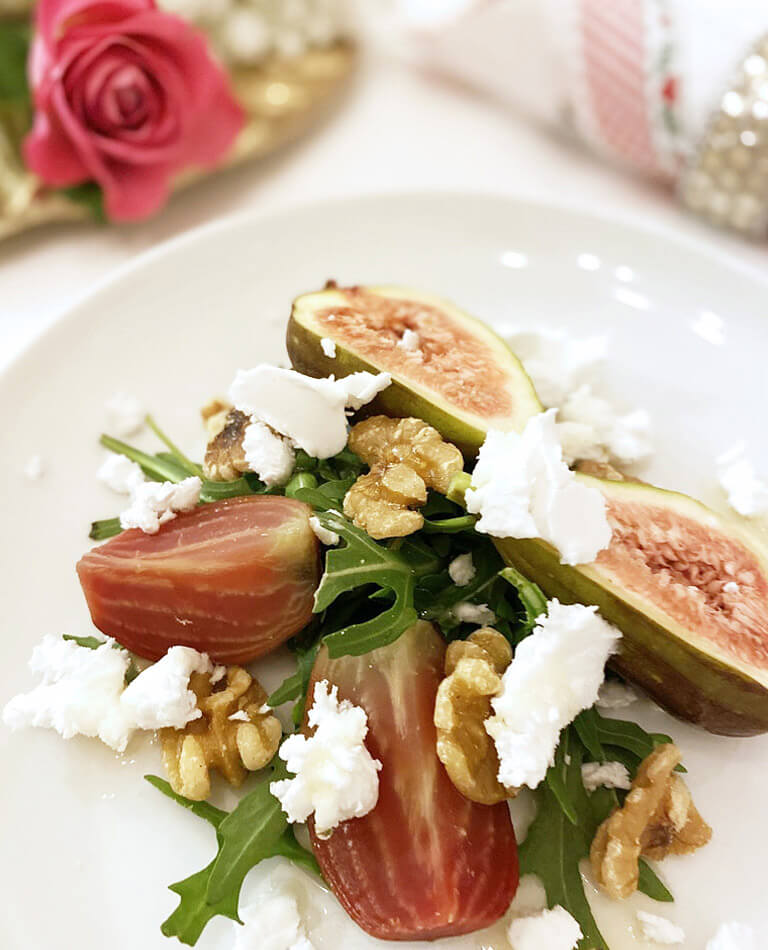 En förrätt med vegansk fetaost och fikon. I bakgrunden ligger en rosa ros.