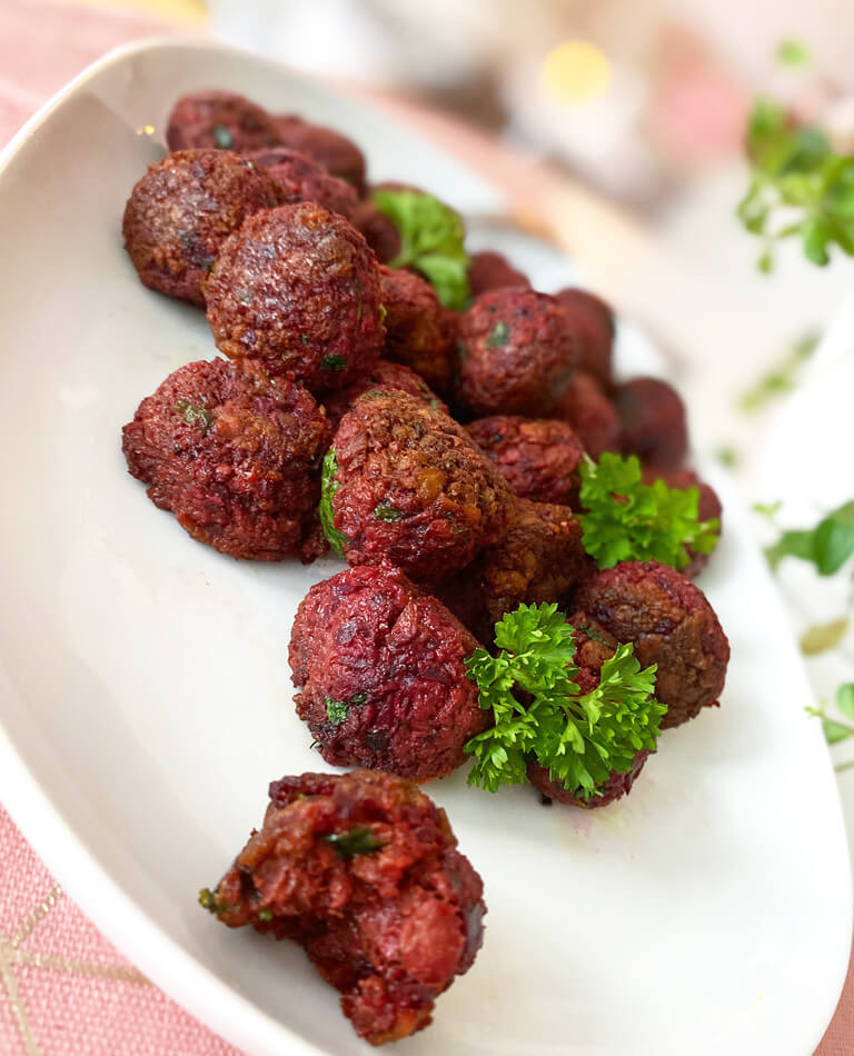 Ett fat med glutenfria vegobullar med rödbeta och persilja.