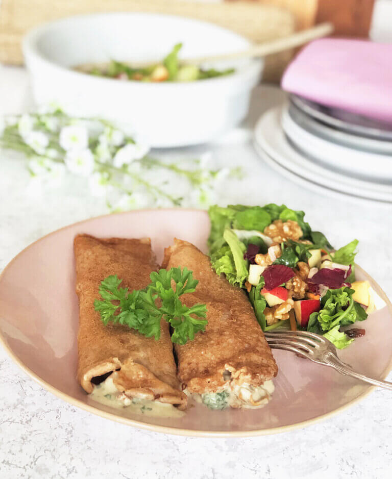 Crepes med svampstuvning och råkostsallad på ett fat.