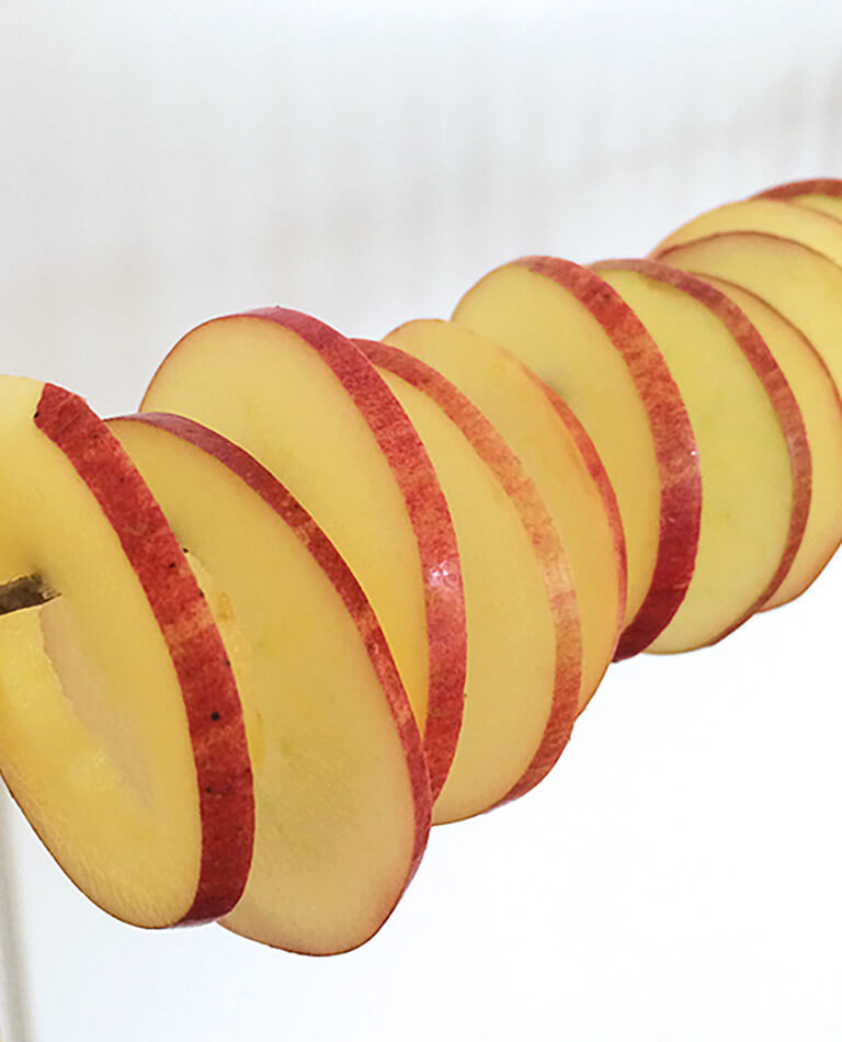 Uppskivade äpplen hänger på en band för att blir lufttorkade äppelchips.