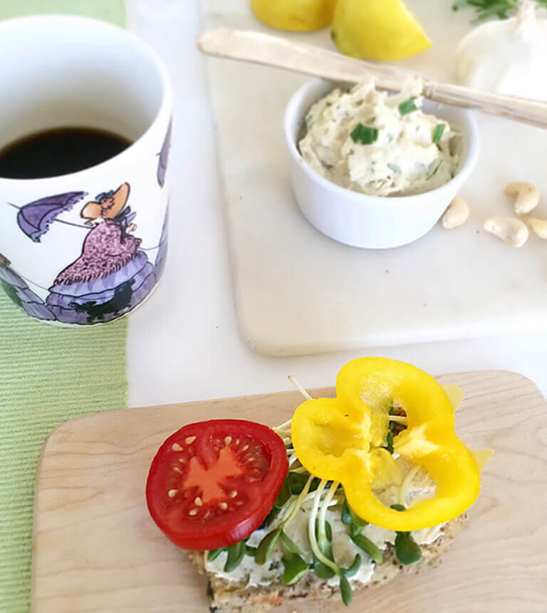 Vegansk ost, mjuk cashewost serverat  med fröknäcke och en kopp kaffe.