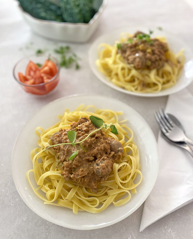 Två fat med vegansk krämig köttfärssås med spagetti.